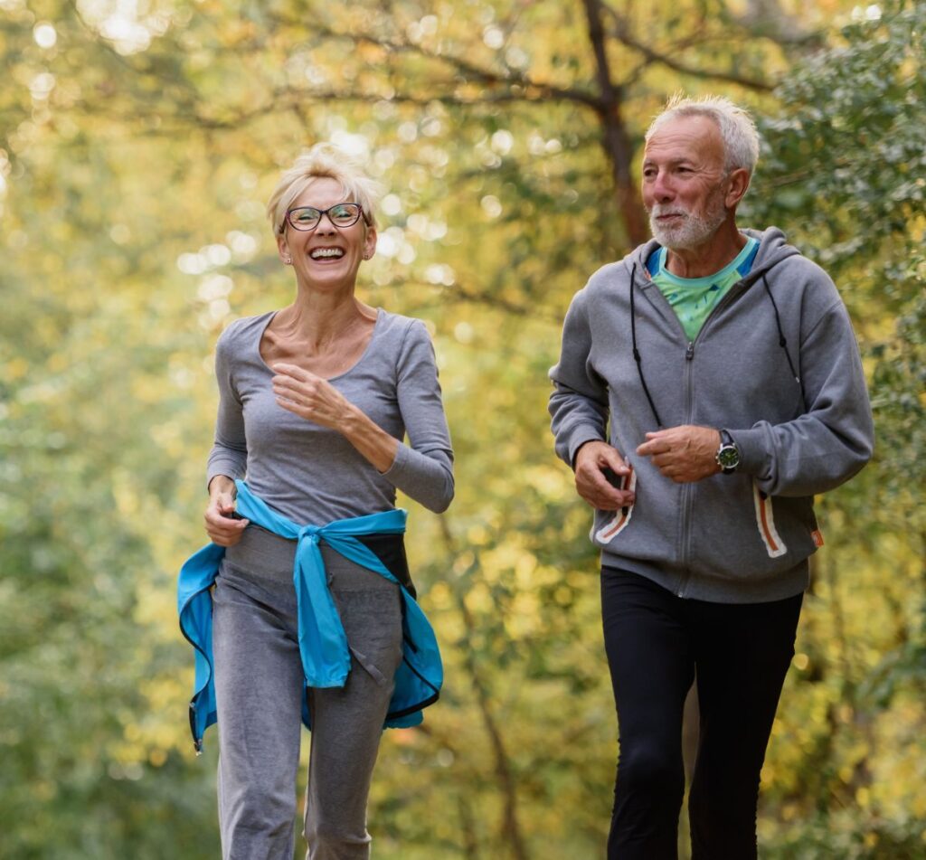 Cheerful active senior couple jogging in the park.
