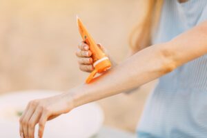 woman putting sunscreen on her arm